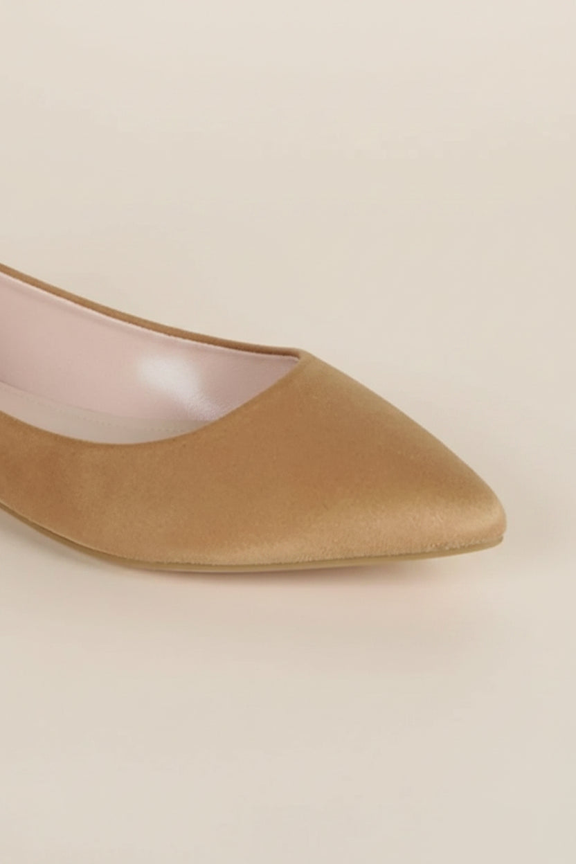 Gold pointed-toe shoe on a light beige background