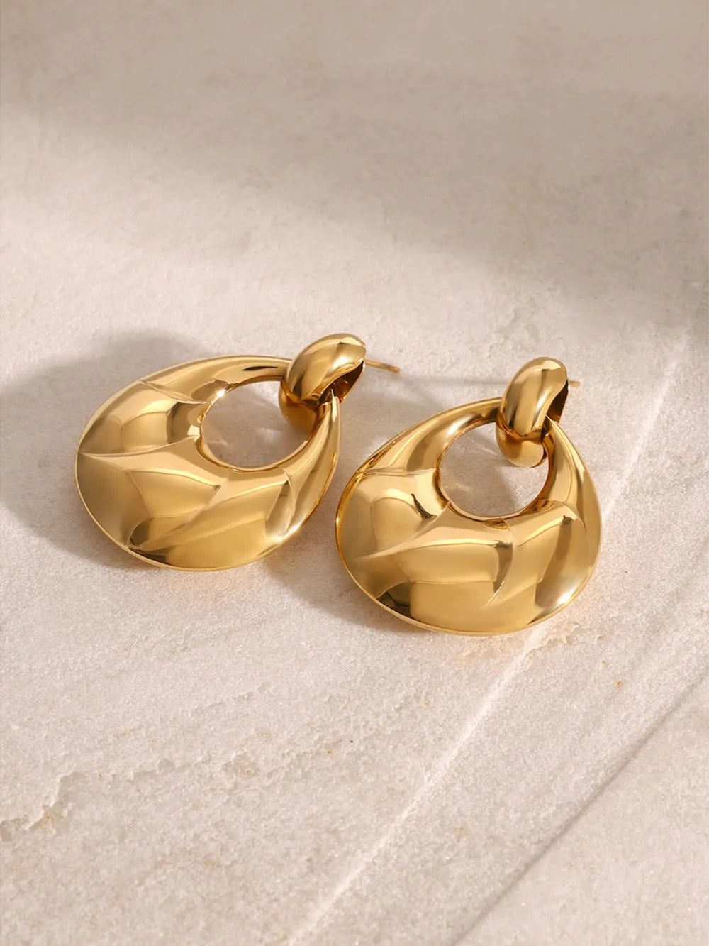 Pair of gold hoop earrings on a light beige surface
