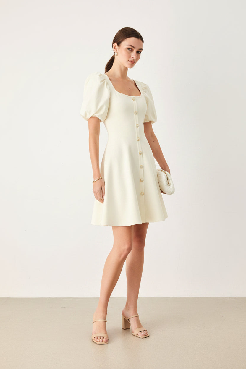 Woman wearing a light yellow dress with puff sleeves on a white background