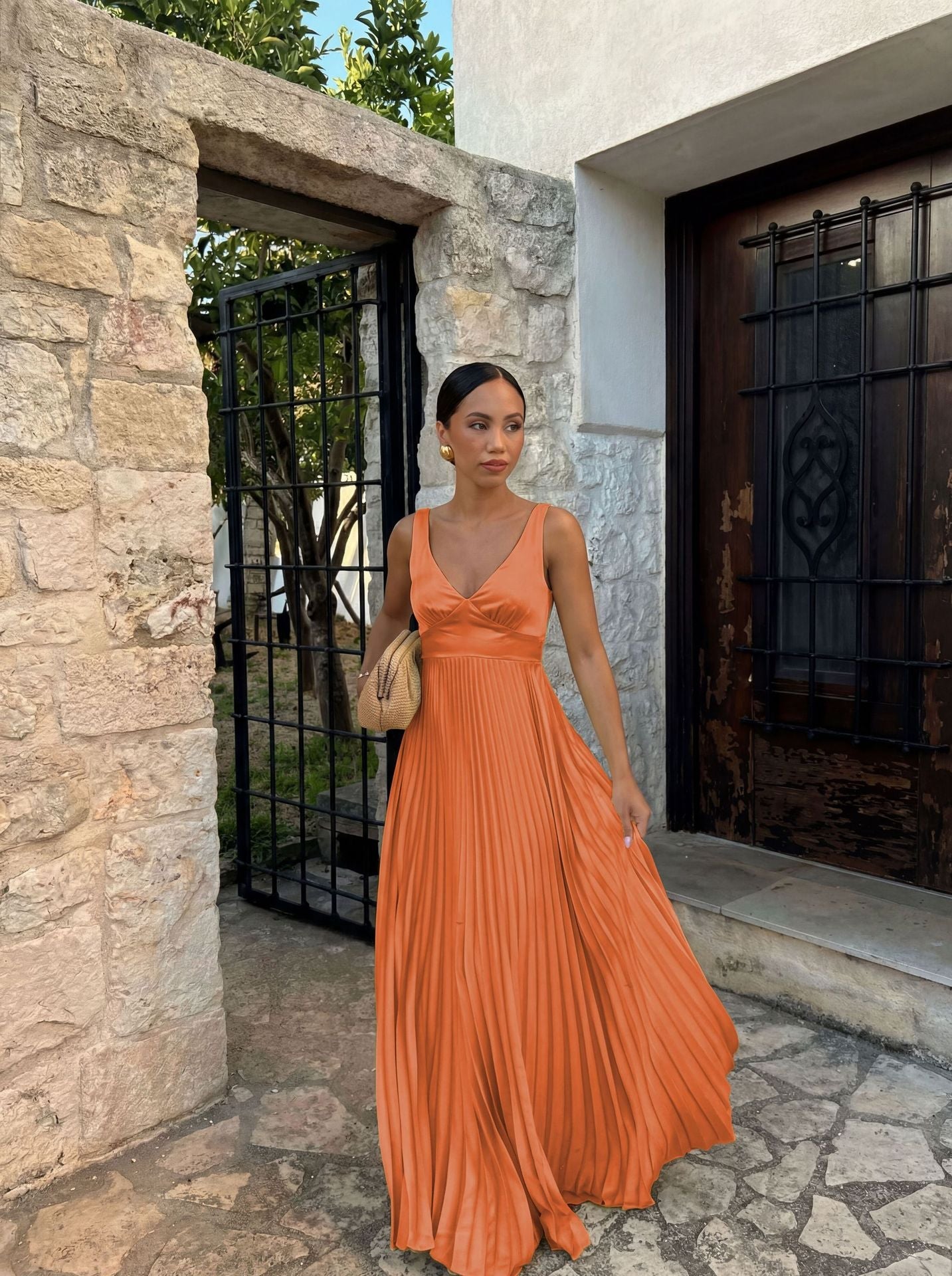 Woman in an orange dress standing in front of a stone building.