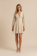 Beige dress with long sleeves worn by a person on a neutral background
