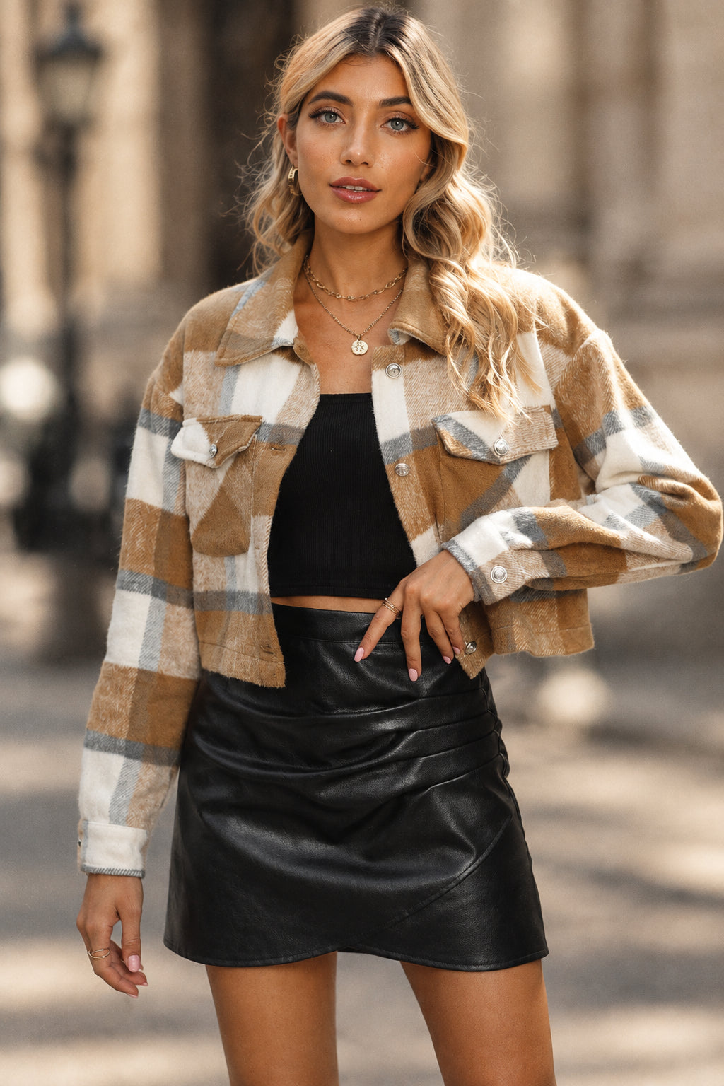 Woman wearing a plaid jacket and black leather skirt against a gray background