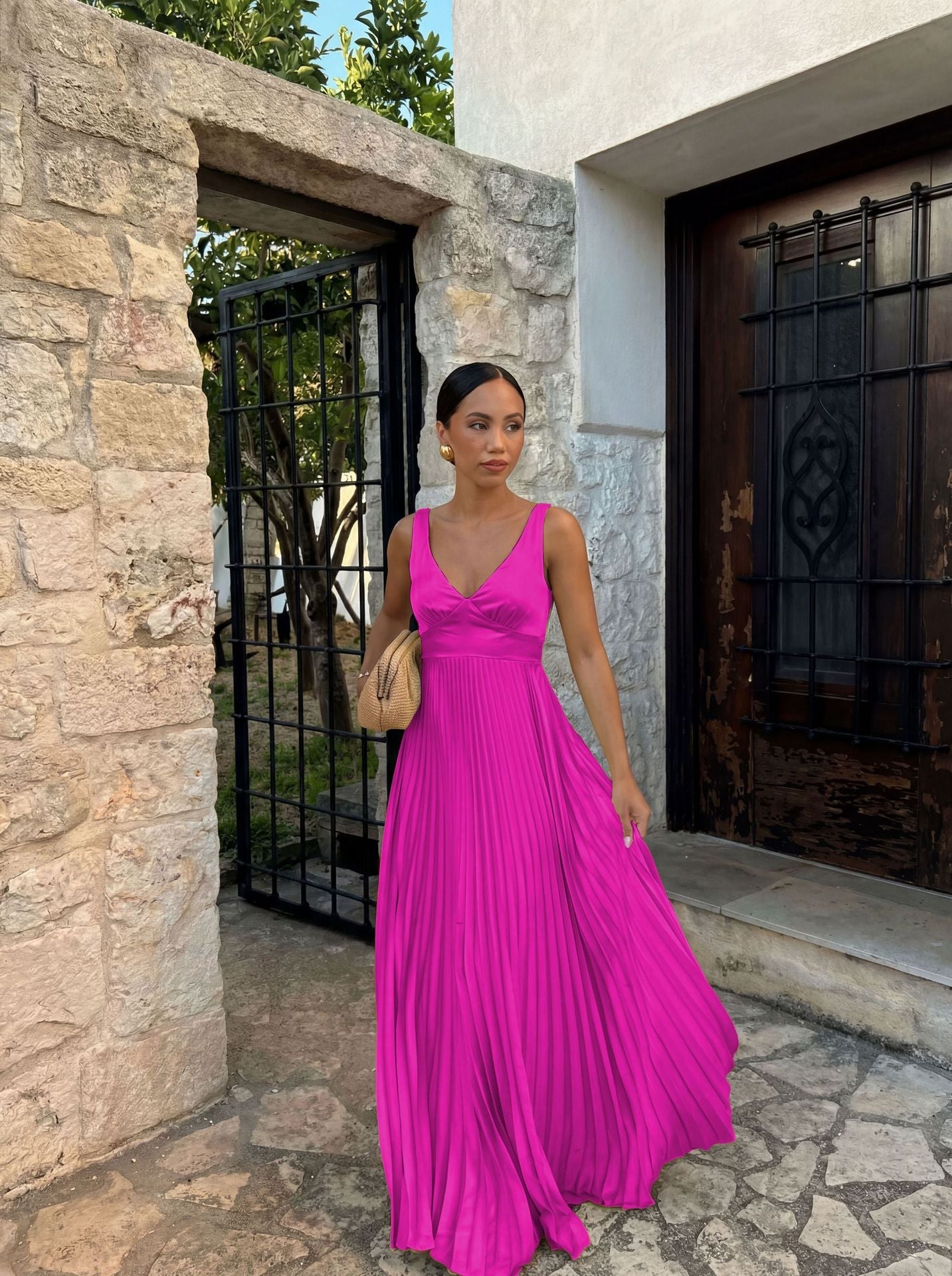 Woman in a pink dress standing in front of a stone building.
