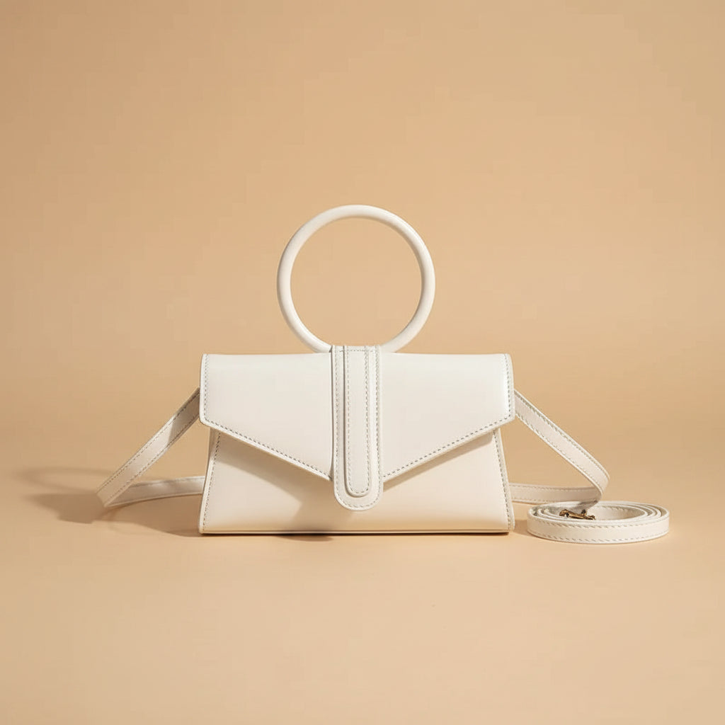 White handbag with circular handle on a book in a cafe setting