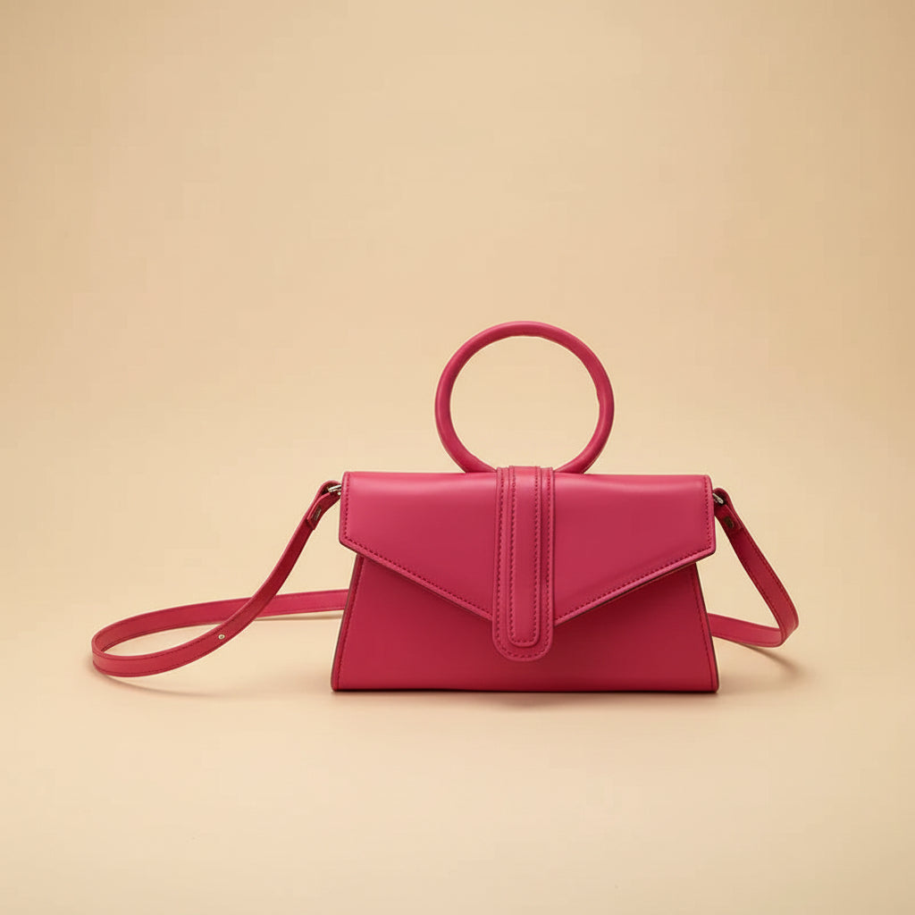 Pink handbag held by a hand on a light fabric background