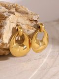 Gold hoop earrings on a textured stone surface