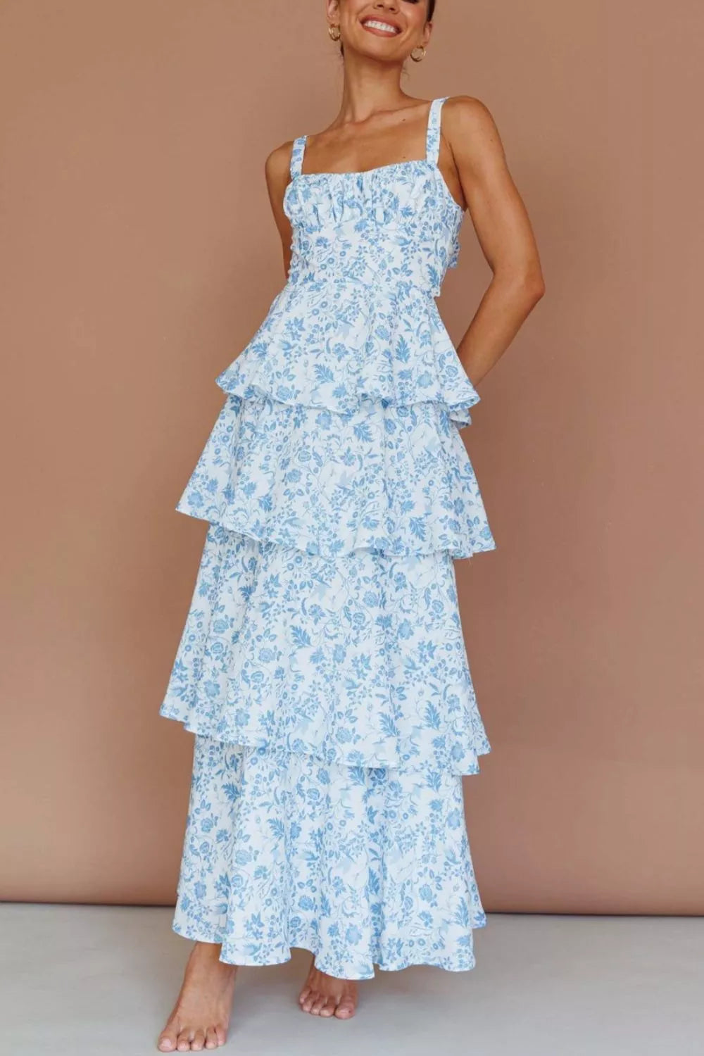 Woman wearing a blue floral tiered dress against a beige background