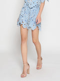 Person wearing a blue floral dress with beige sandals on a white background